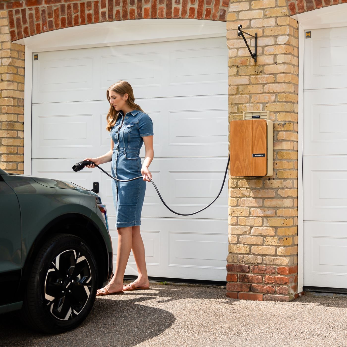 Level 2 home EV charge point mounted beside a garage door with a car charging